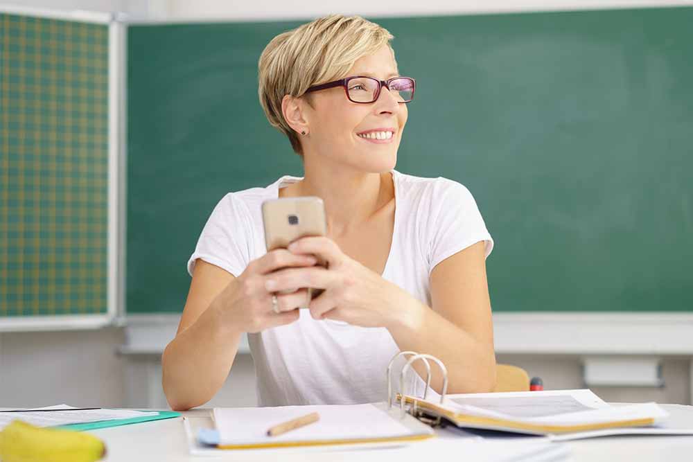 teacher with mobile phone in classroom