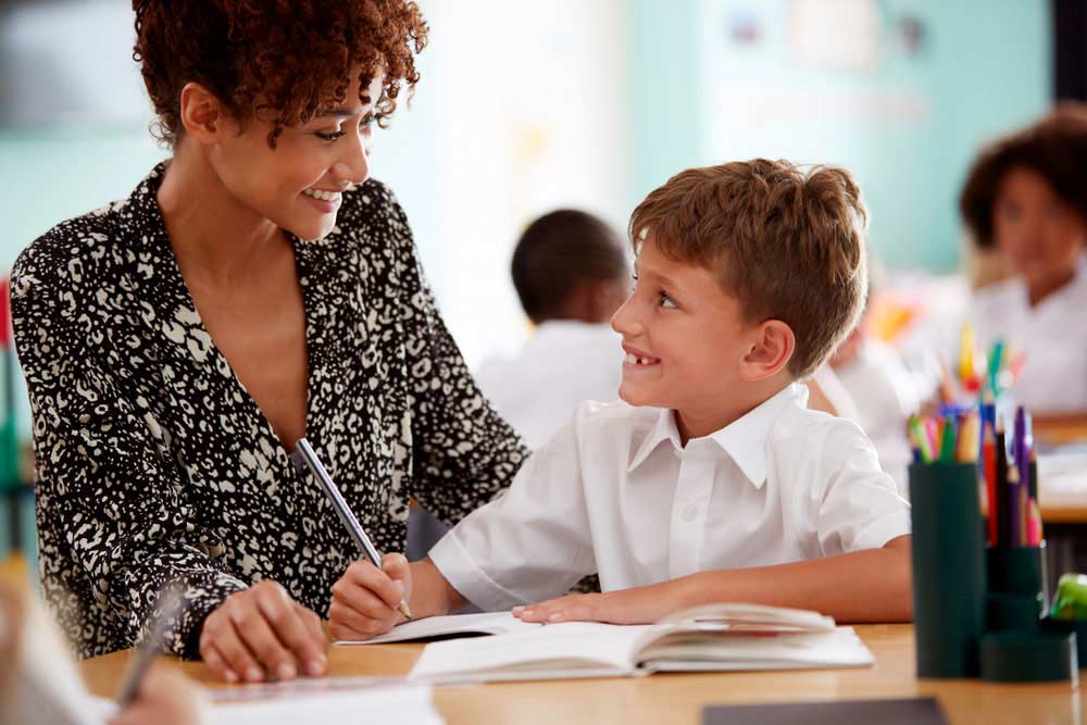 teacher working with young student in classroom